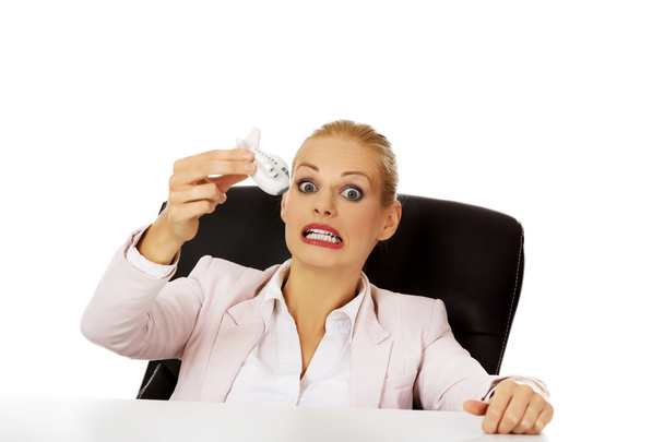 Business woman sitting behind the desk and holding a toy plane - Foto, Imagen