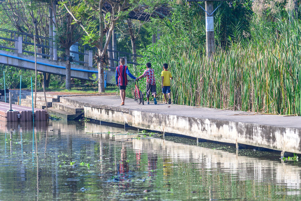 Boys walking along the canal with bicycle. - 写真・画像