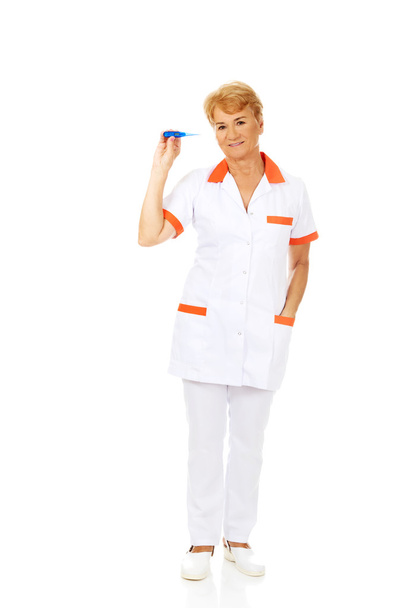 Smile elderly female doctor or nurse holding thermometer - Photo, Image