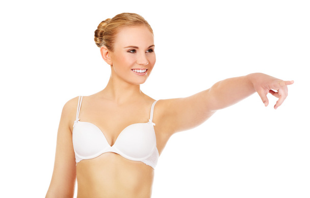 Young woman in white bra pointing for copyspace or something - Фото, зображення