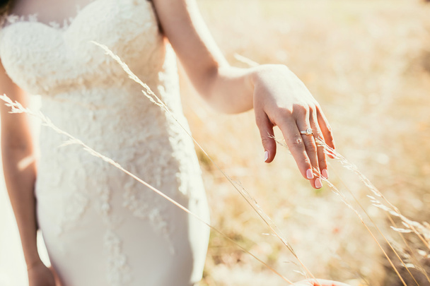 beautiful wedding ring on bride hand touching ear on field in su - Foto, afbeelding