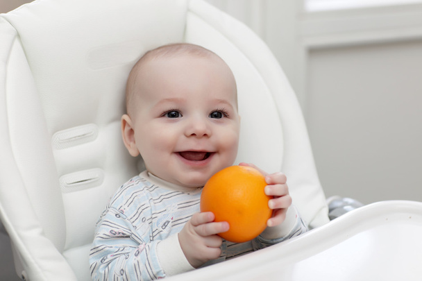 Smiling baby with orange - Valokuva, kuva