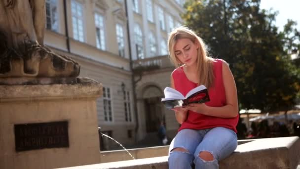 Bella dama sonriendo mientras lee su libro en el centro de la ciudad
 - Metraje, vídeo