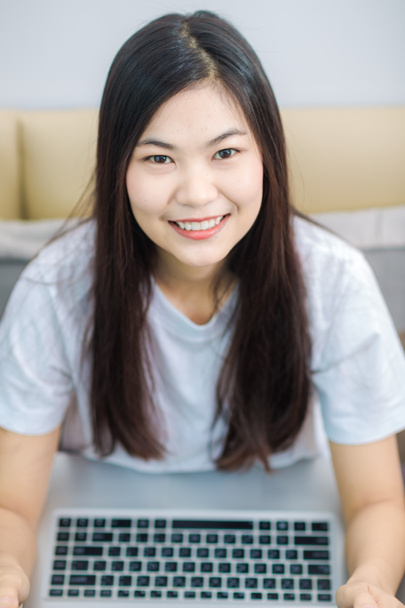 Aasian mustat hiukset nainen käyttää kannettavaa makuuhuoneessa
 - Valokuva, kuva