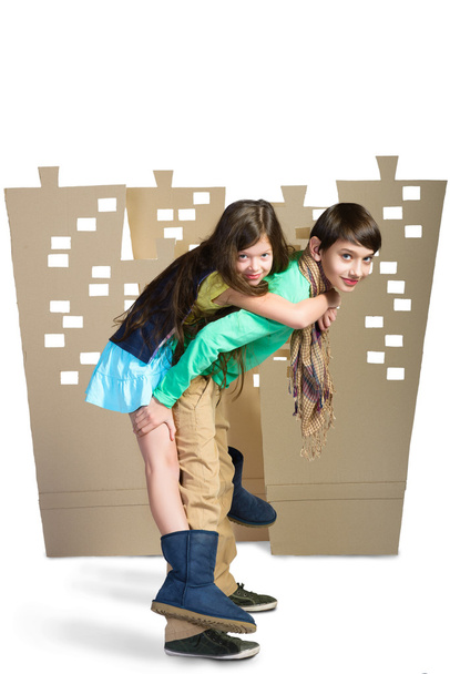 Concepto de amor. niño sosteniendo a la chica en el fondo de la ciudad de cartón. aislar blanco
 - Foto, imagen