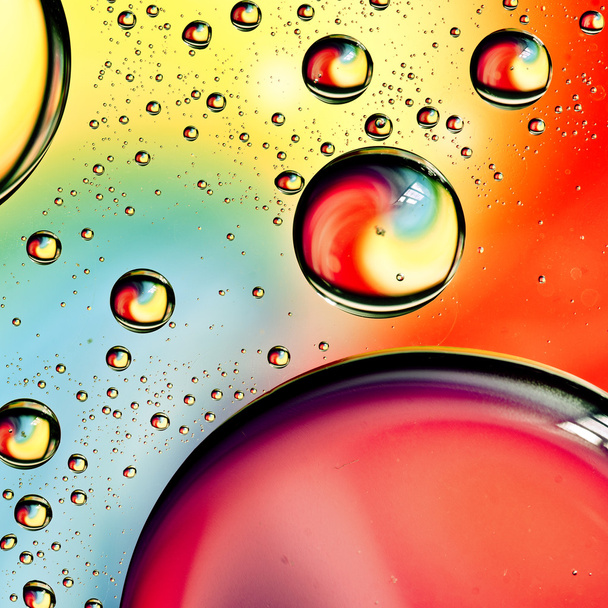 Close-up on water drops background on rainbow colors surface. Water droplets on glass with reflections in them. - Фото, изображение