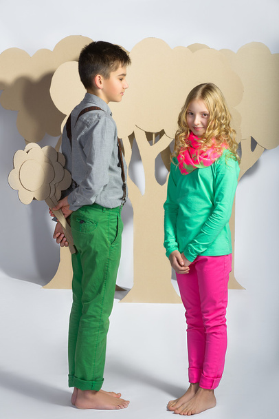 Love concept. Couple of kids. boy gives a girl cardboard flowers - Фото, зображення