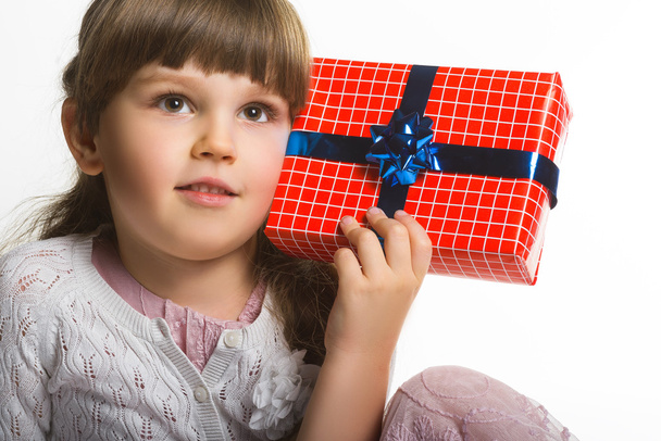 Happy little girl put gift box to the ear  isolated on white background - Фото, зображення