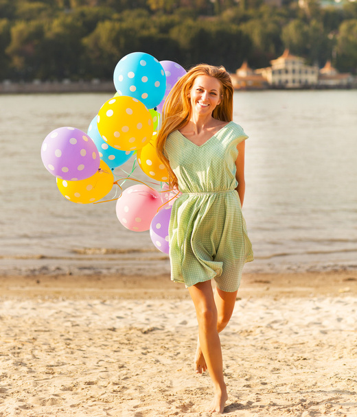 Happy woman on the beach with colored polka dots balloons - Fotó, kép