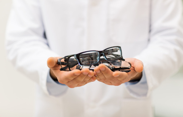 close up of optician with glasses at optics store - Foto, Bild