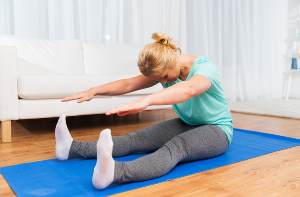 woman exercising on mat at home - Фото, изображение