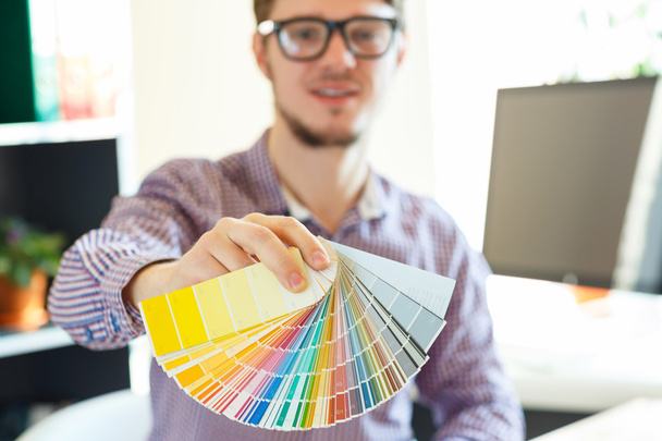 Hombre joven mirando a una paleta de pintura de color
 - Foto, Imagen