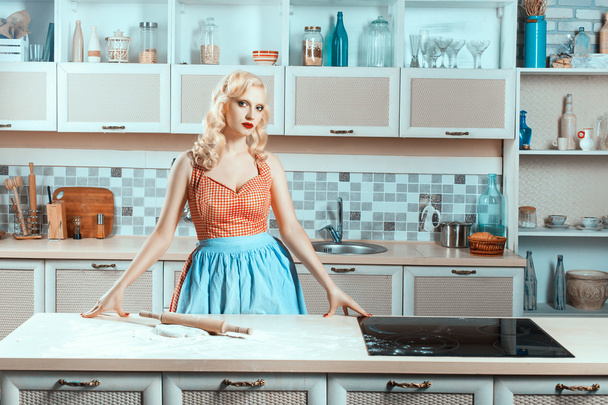 Blonde girl standing in the kitchen next to stove. - Zdjęcie, obraz