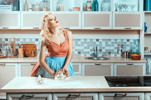 Белокурая девушка на кухне замешивает тесто. - Фото, изображение