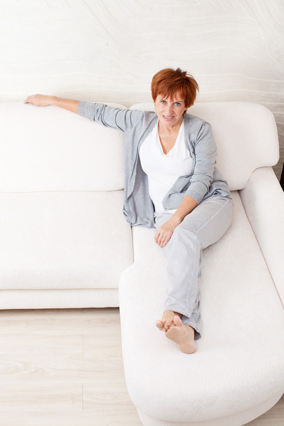 Happy mature woman on sofa - Foto, imagen