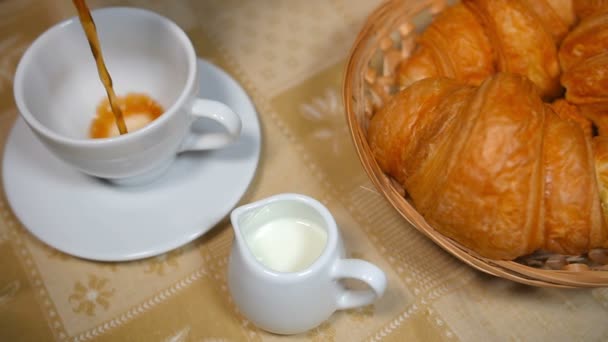 Kaffee in Tasse mit Croissant gießen - Filmmaterial, Video