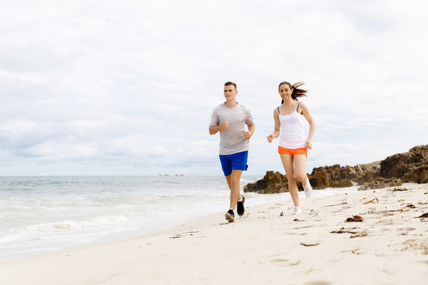Corredores. Jovem casal correndo na praia
 - Foto, Imagem