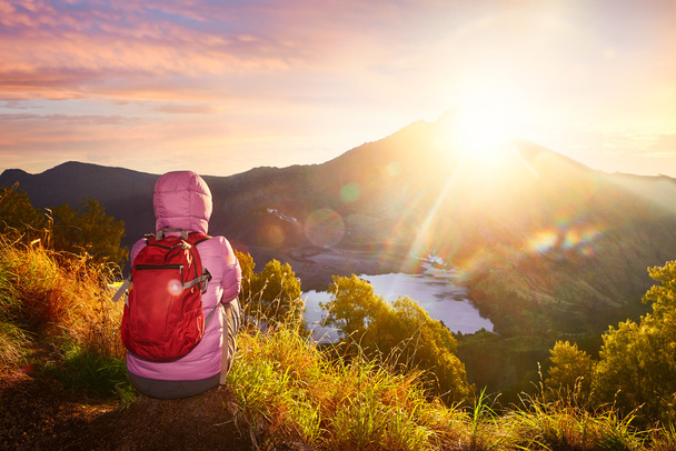 Женщина с туристом наслаждается видом на восход солнца в высоких горах
. - Фото, изображение