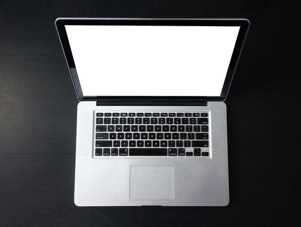 Open laptop with isolated screen on dark wooden desk - 写真・画像