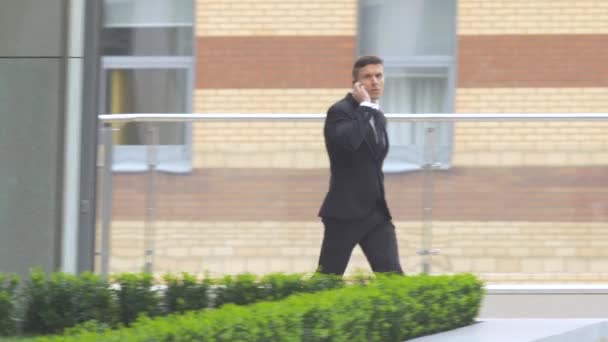 businessman out of the building and speaking on the phone - Séquence, vidéo
