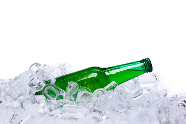 Beer bottle in ice cubes over white background - Φωτογραφία, εικόνα