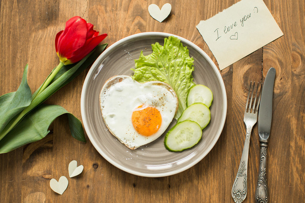 Breakfast on Valentine's Day with fried eggs in the shape of a heart and fresh vegetables. - Valokuva, kuva