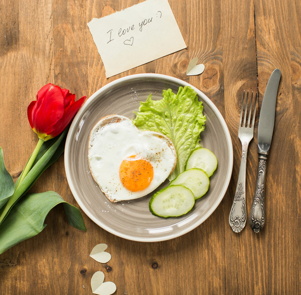 Breakfast on Valentine's Day with fried eggs in the shape of a heart and fresh vegetables. - Photo, image