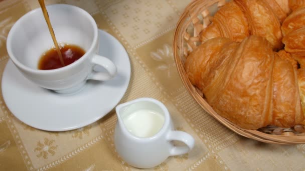Kaffee in Tasse mit Croissant gießen - Filmmaterial, Video