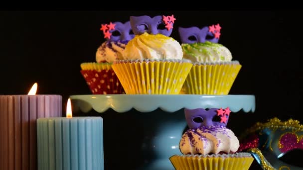 Mardi Gras Cupcakes με μωβ μάσκα toppers με αναμμένα κεριά, αργή μεγέθυνση και σμίκρυνση. - Πλάνα, βίντεο