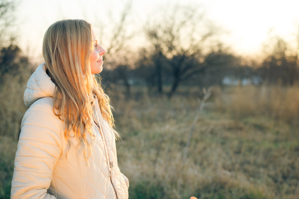 Glimlachend jonge vrouw op buitenshuis zonnige achtergrond kopie ruimte - Foto, afbeelding