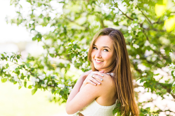 Kaunis nuori nainen kevään puutarhassa omenankukan joukossa, pehmeä keskittyminen
 - Valokuva, kuva