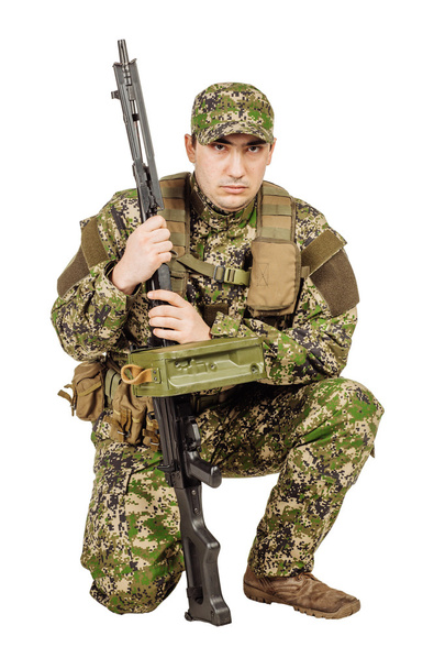 military, profession, people and war concept - male soldier in camouflage with a rifle on a white wall - Fotó, kép