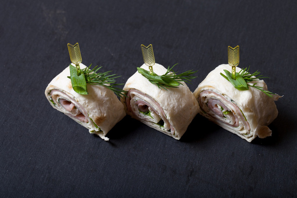 Small rolls with ham, cheese and pita on skewer on a black slate - Valokuva, kuva