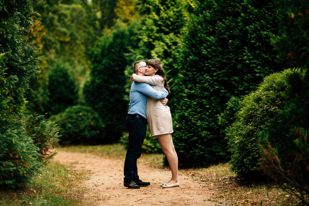 Pregnant beautiful woman and her handsome husband lovely hugging in autumn park. - Фото, изображение
