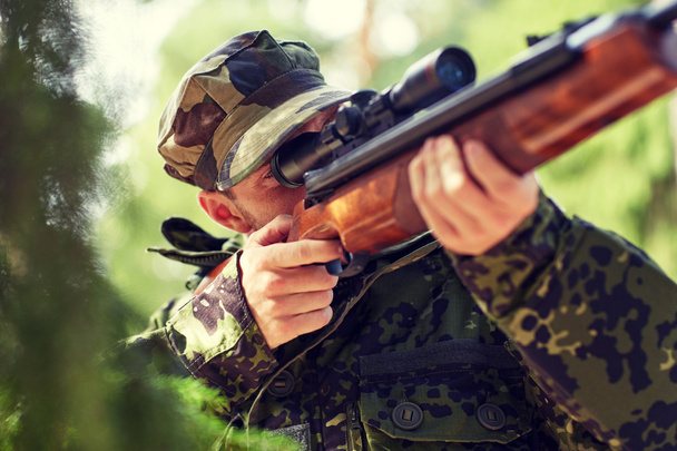 sotilas tai metsästäjä ampuu aseella metsässä
 - Valokuva, kuva