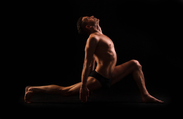 Practice yoga and gymnastics on a black background - Foto, afbeelding