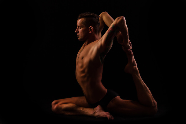young man doing yoga and gymnastics, pigeon pose - Photo, Image