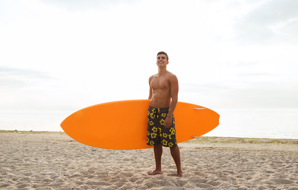 smiling young man with surfboard on beach - Valokuva, kuva