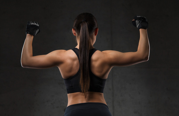 young woman flexing muscles in gym - 写真・画像