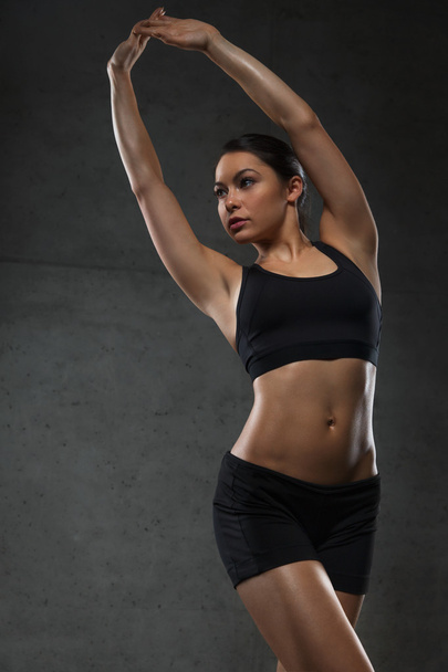 νεαρή γυναίκα να ποζάρει και να δείχνει τους μυς στο γυμναστήριο - Φωτογραφία, εικόνα