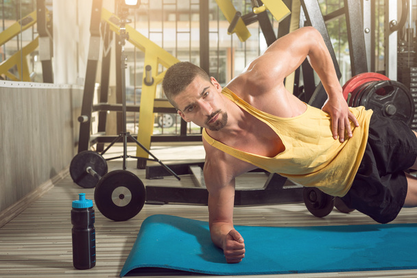 Man doing side plank exercise in gym - Foto, Bild
