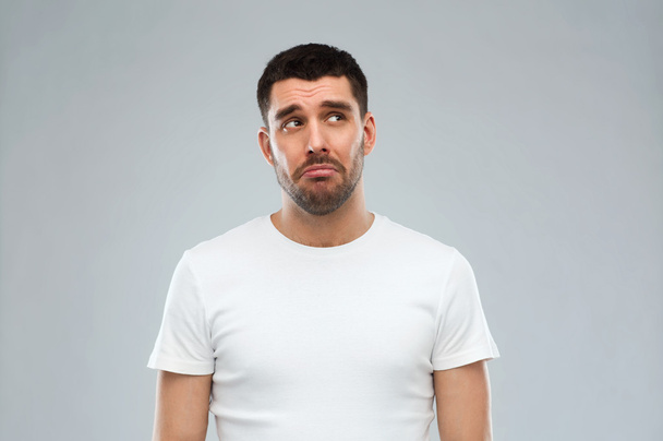unhappy young man over gray background - Foto, Imagen