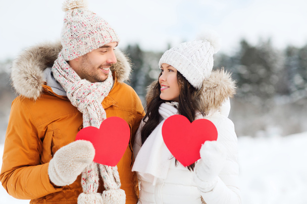 happy couple with red hearts over winter landscape - 写真・画像