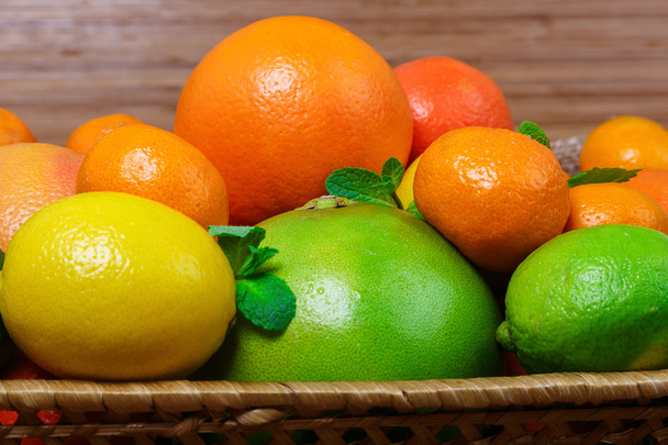 Citrus in a wicker basket on wooden background - Photo, Image