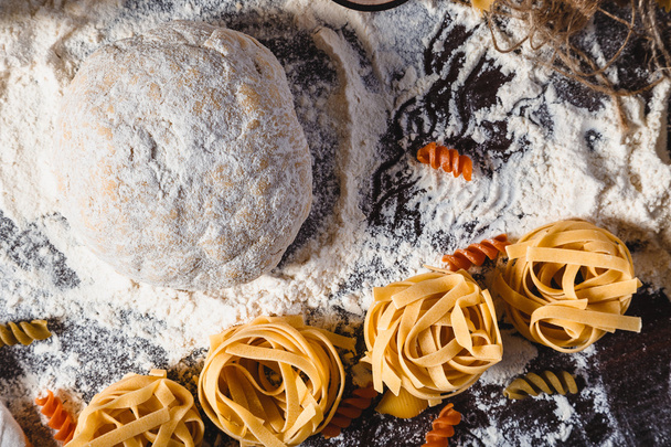 Pasta on dark wooden background with dough, eggs, oil and flour close-up macro - Valokuva, kuva