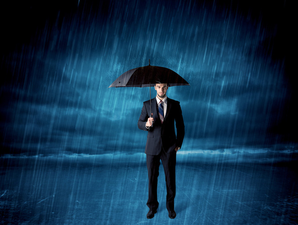 Business man standing in rain with an umbrella - Fotoğraf, Görsel