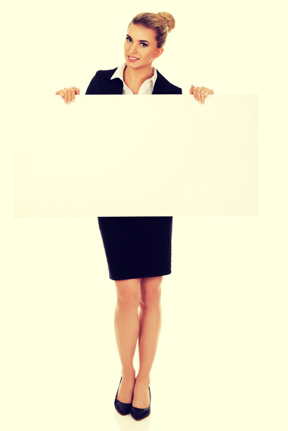 Happy businesswoman holding empty banner. - Фото, изображение