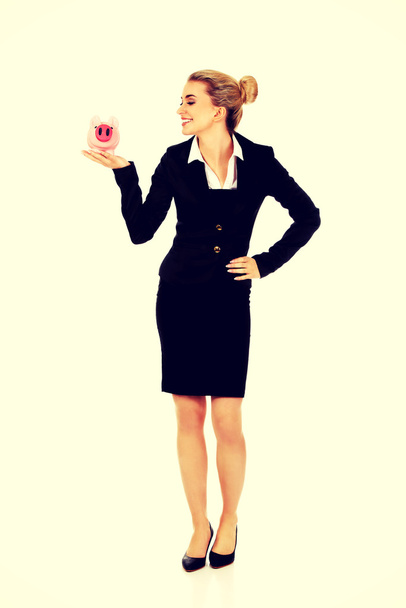Young businesswoman saving money in piggybank - Zdjęcie, obraz