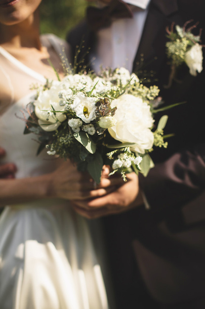Bride and groom holding bridal bouquet - Fotografie, Obrázek