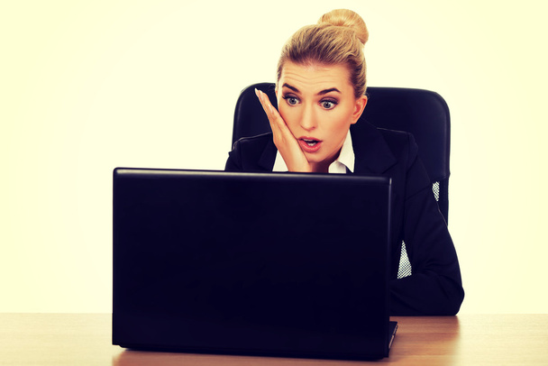 Surprised and curious businesswoman cannot believe what she sees in the laptop screen - Фото, зображення